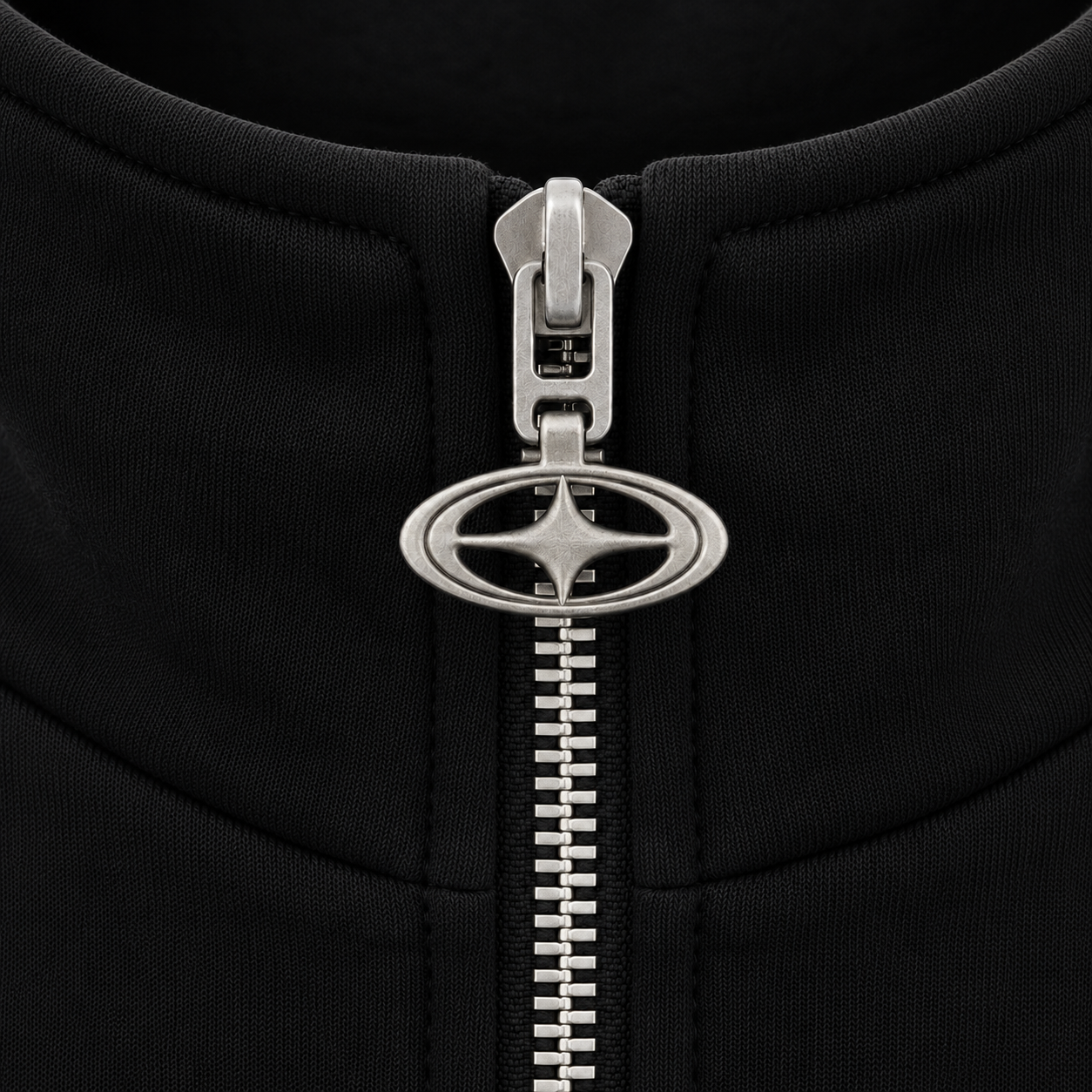 Close-up of a black zippered garment featuring a distinctive silver oval zipper pull with a four-pointed star design.