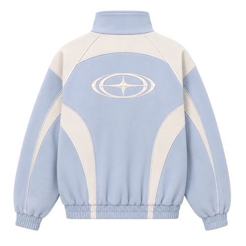 A light blue and cream color-blocked track jacket shown from the back, featuring a high mock neck, elastic cuffs and hem, and a large white geometric logo on the upper back.